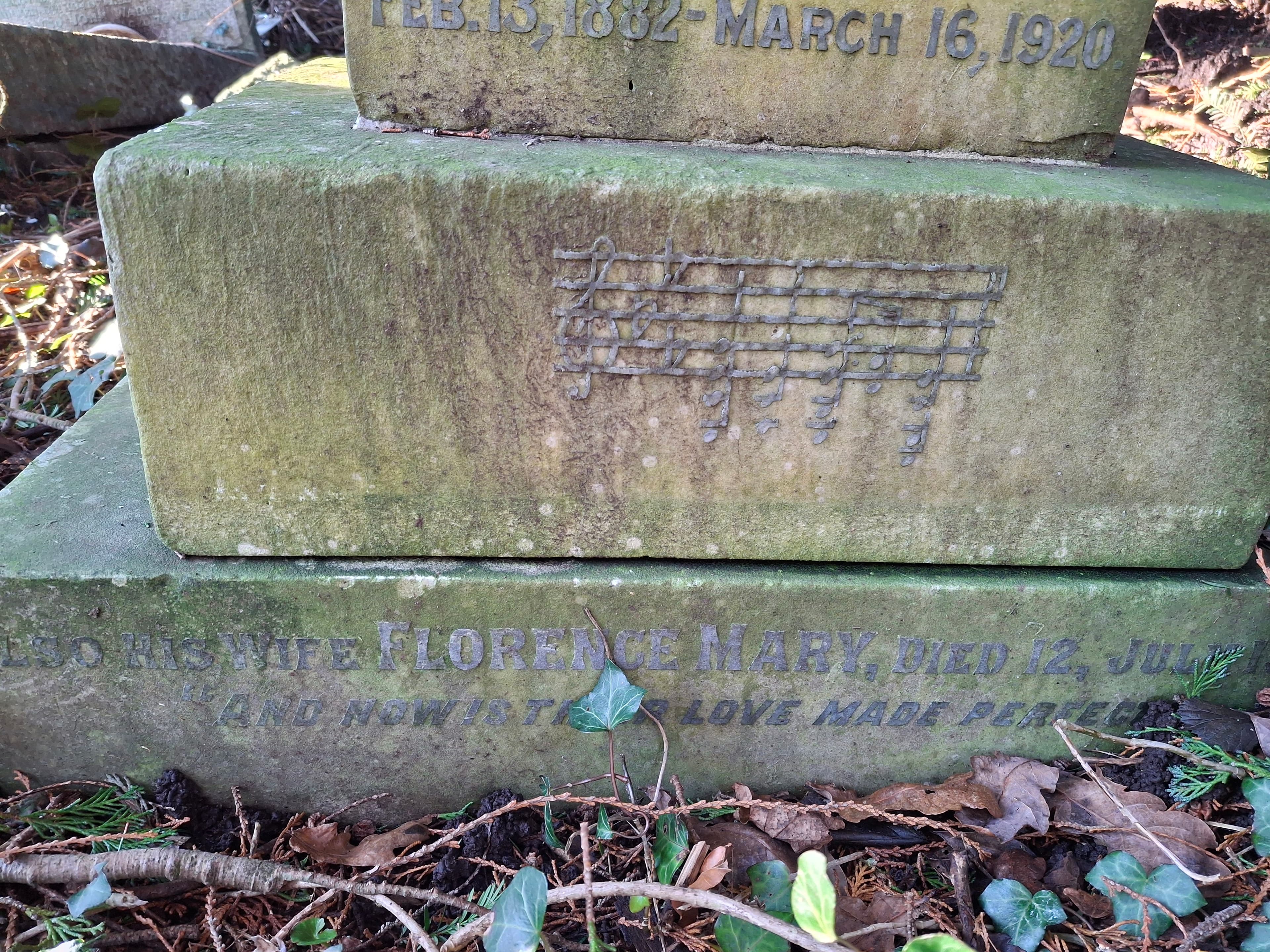 A white gravestone with musical notation carved into it